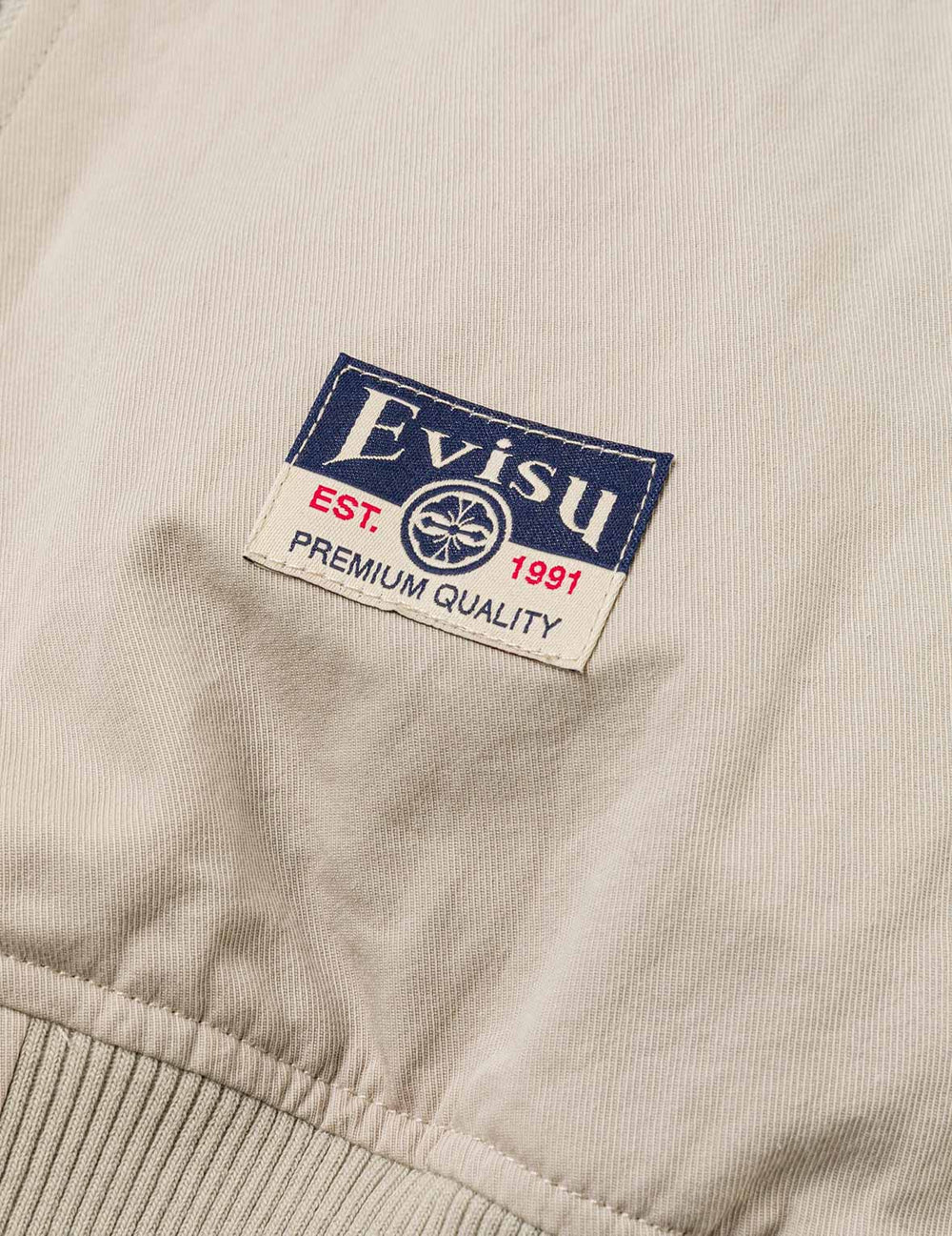 EVISU bomberjakke i grå med Daicock-print, blødt stof og klassisk stil, vises i dette billede.