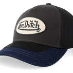 Von Dutch trucker cap med oval patch og skjolddesign i grå, sort og navy, vises med justerbar rem foran og mesh bag.