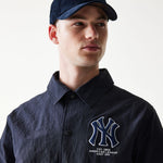 Dame i New Era MLB coaches jakke i navy med Yankees logo, sporty baseballtrøje med frontlommer og hætte.