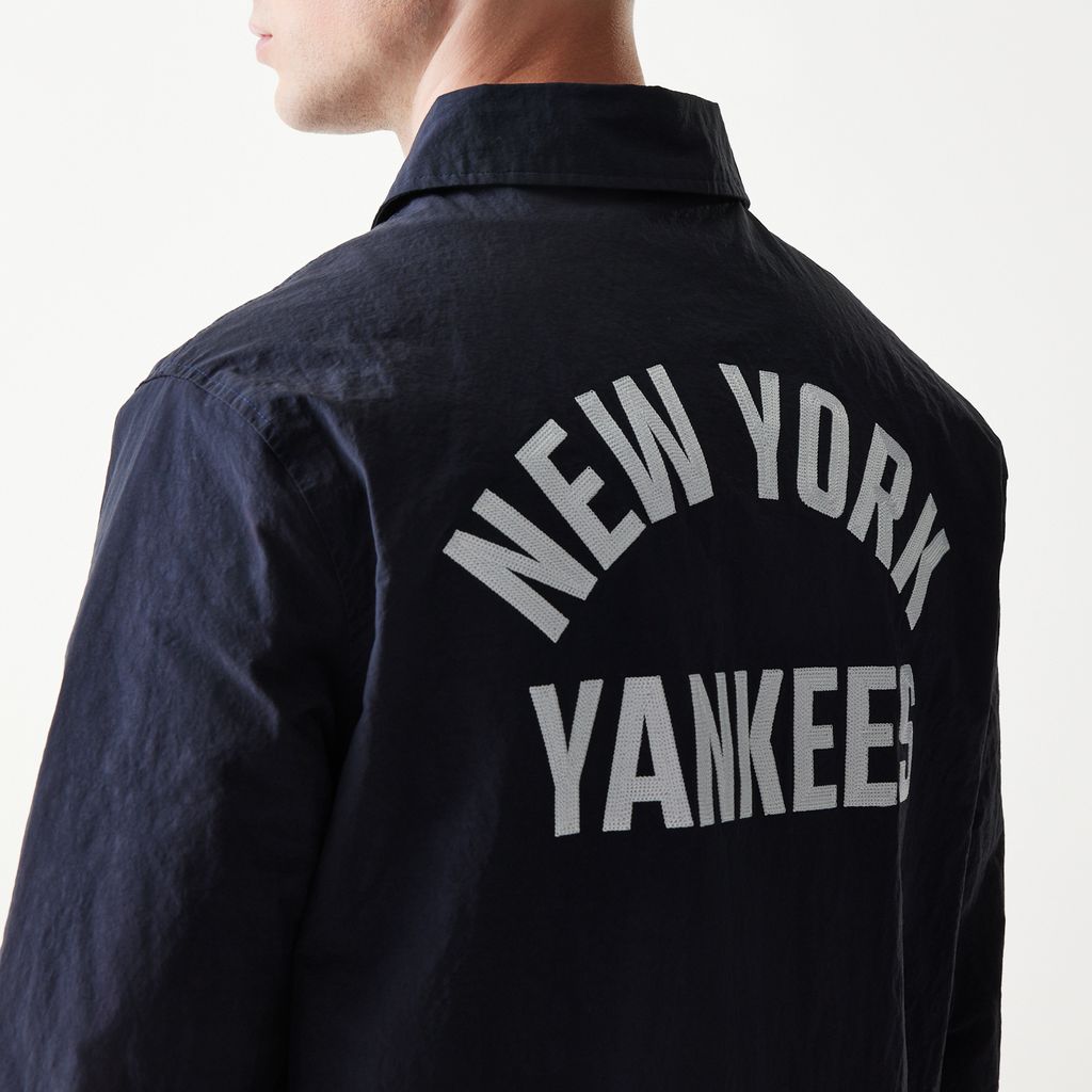 Dame i New Era MLB Coaches Jakke i marineblå med Yankees logo, sportstøj til fans af baseball og New York Yankees.