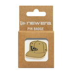 Gullfarget New Era NE Cap Badge, taskeaccessory med logo, synlig på billedet.