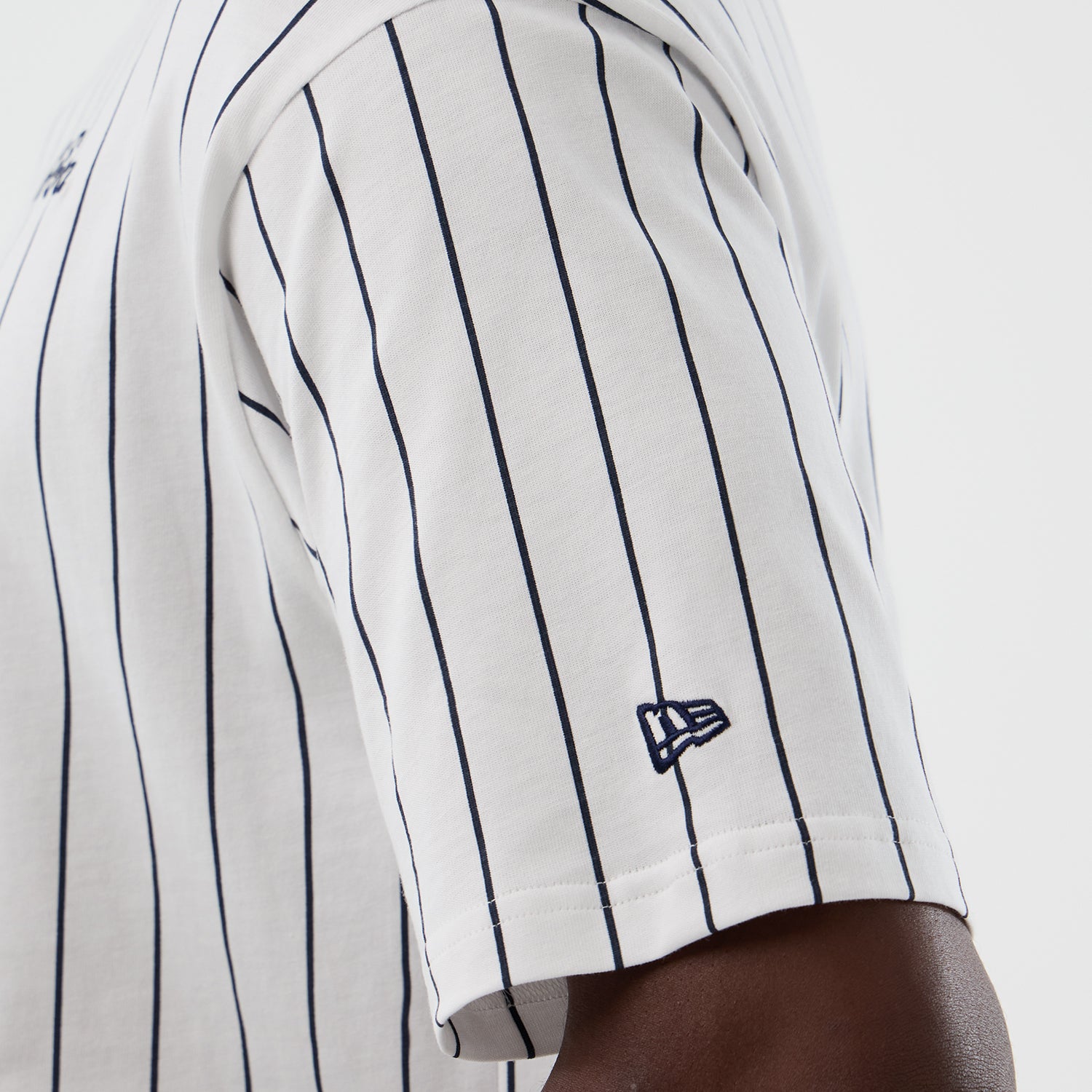 Hvid og navy New Era oversized T-shirt med pinstribe-mønster, afslappet pasform og logo-detail foran.