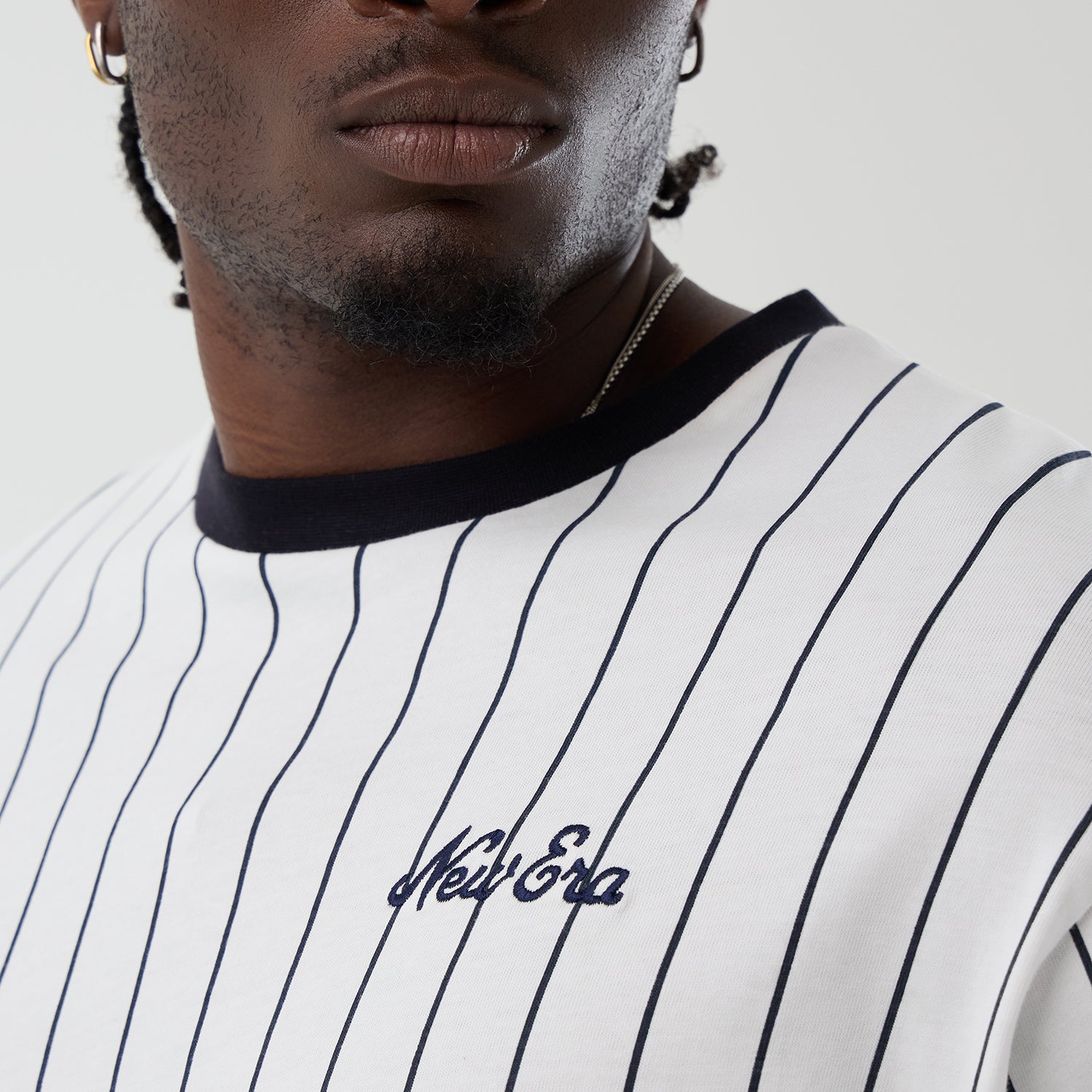 Hvid og navy New Era oversize T-shirt med pinstripes, afslappet pasform og logo detaljer, set fra front.