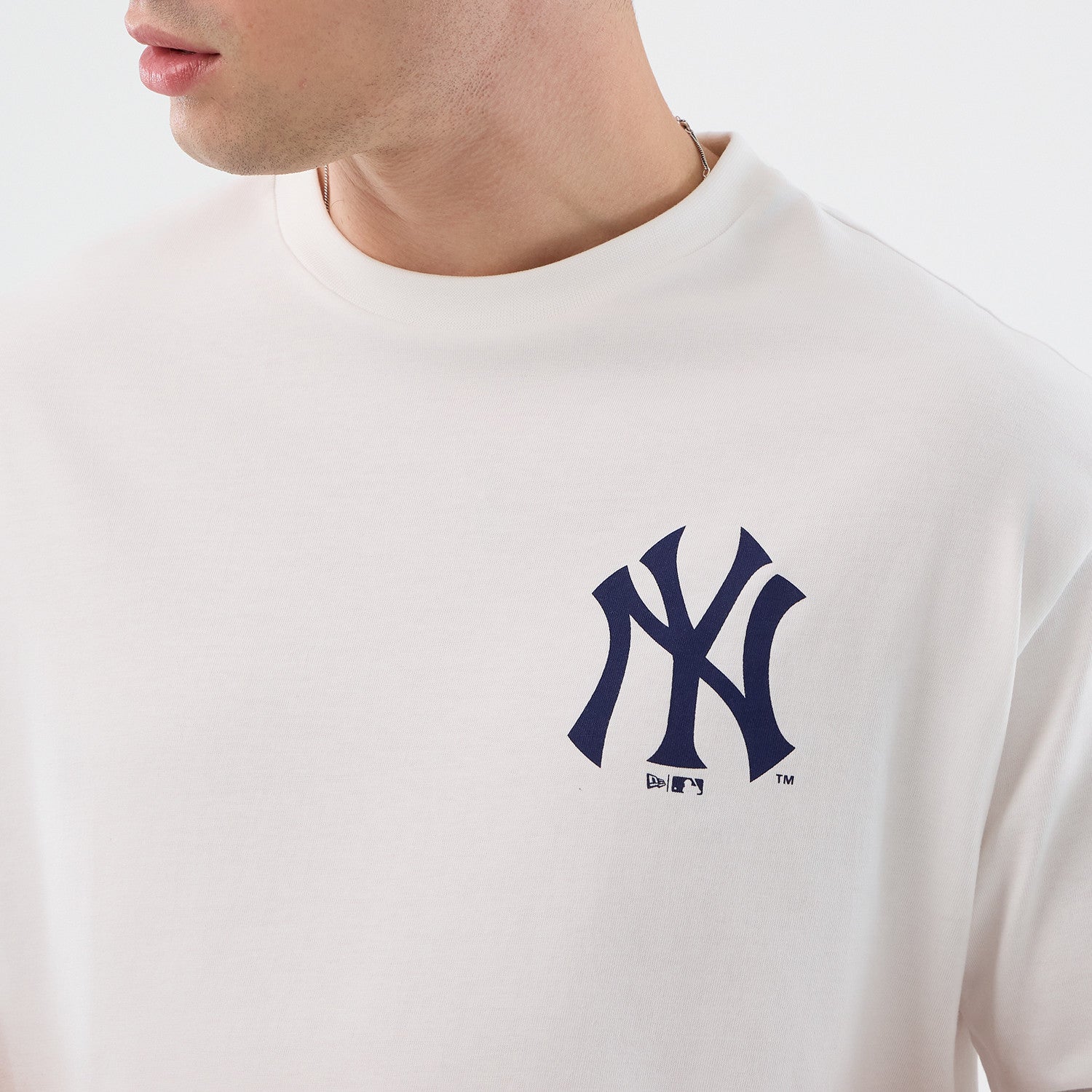 Hvid New Era MLB-cap grafikt-shirt med oversized pasform og New York Yankees-logo, synlig på billedet.