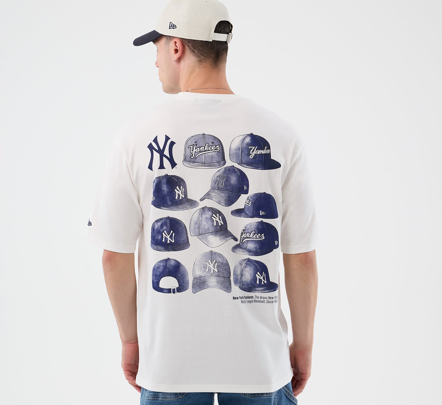 Hvid New Era MLB-cap grafisk T-shirt med oversized pasform og Yankees-logo, detaljeret visning af design og stoffets tekstur.