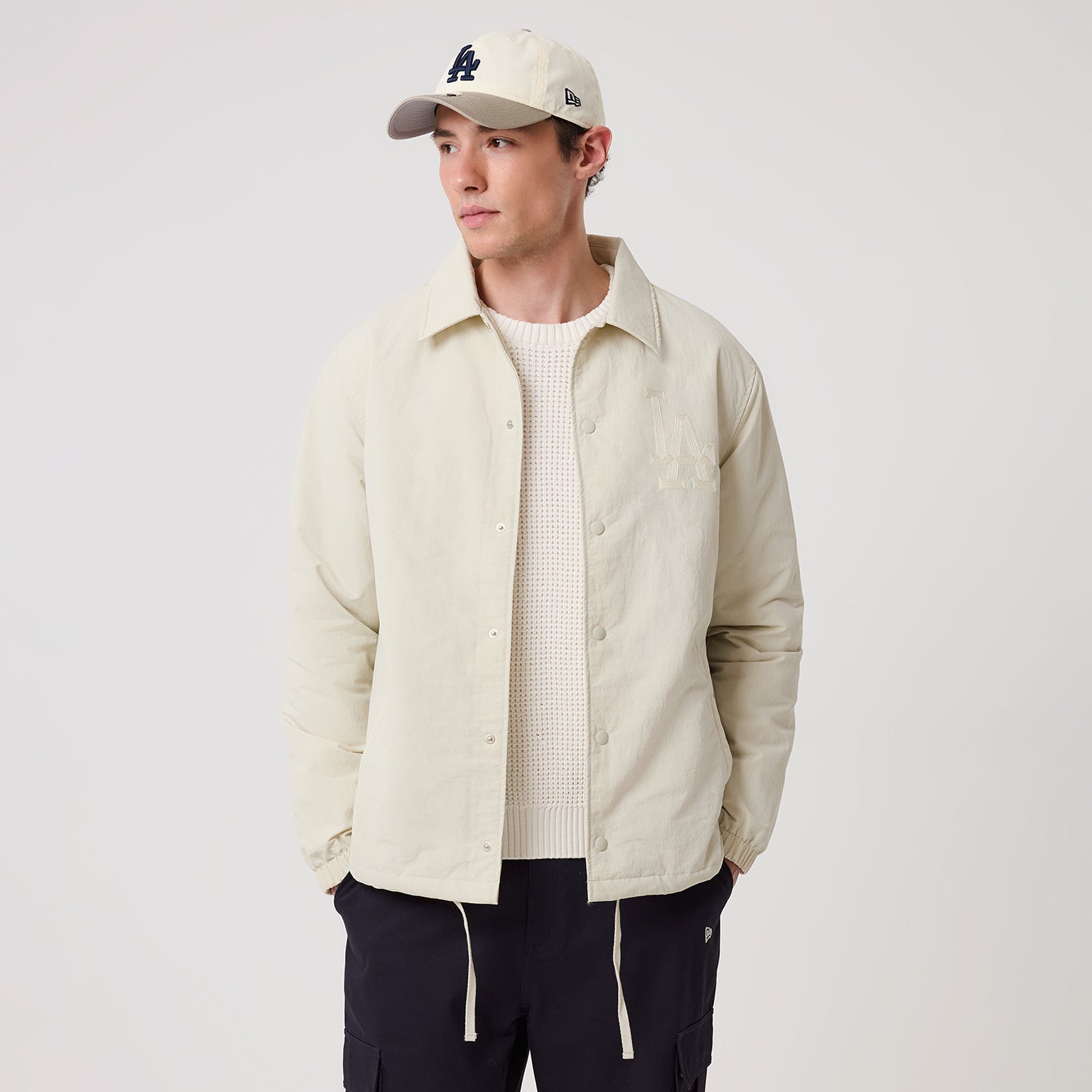 Beige New Era MLB trænerjakke med logo, langærmet jakke til sport og fritid, vist på model foran neutral baggrund.