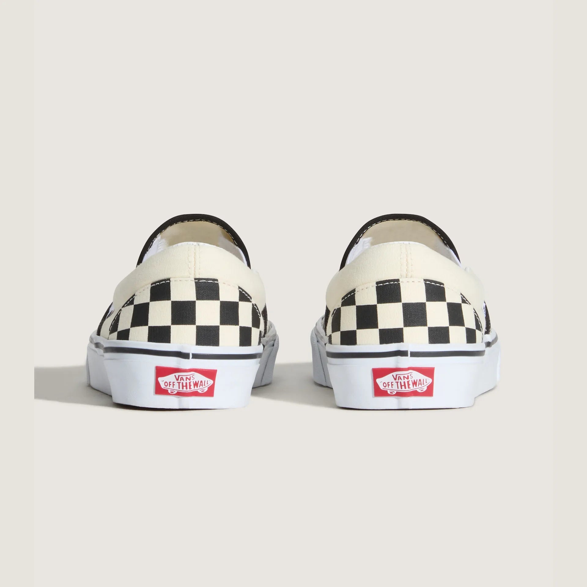 Sort og hvid checkerboard VANS sneakers i slip-on stil, vist fra siden med synlige elastikindlæg og flad sål.