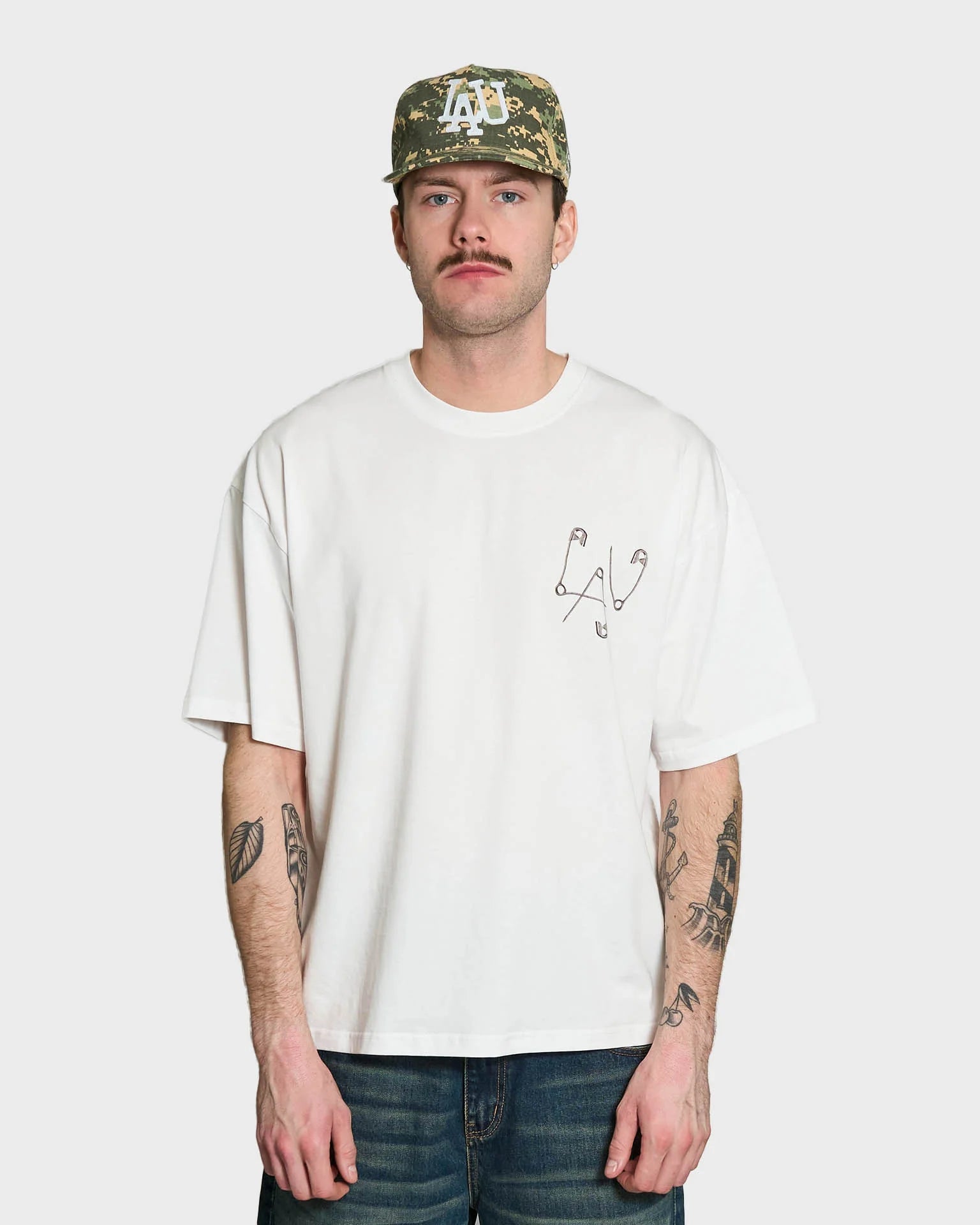 Lau Lau Safety Pin Tee SS i hvid, kortærmet T-shirt med sikkerhedsnålsdetaljer, afslappet casual stil, foran vises logo.