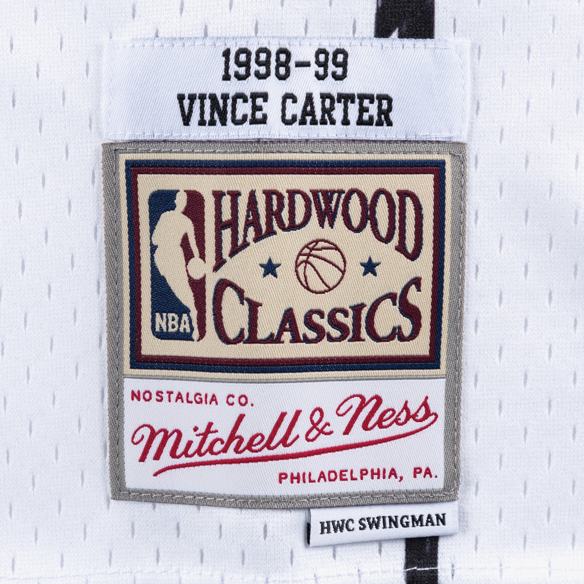 Hvid Mitchell & Ness Vince Carter 1998 SWINGMAN basketballtrøje, vises på model med detaljeret fokus på jerseyens design.