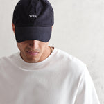 Navy Spencer sport cap fra Wax London i bomuld med justerbar rem og sporty design, vist foran på modellen.