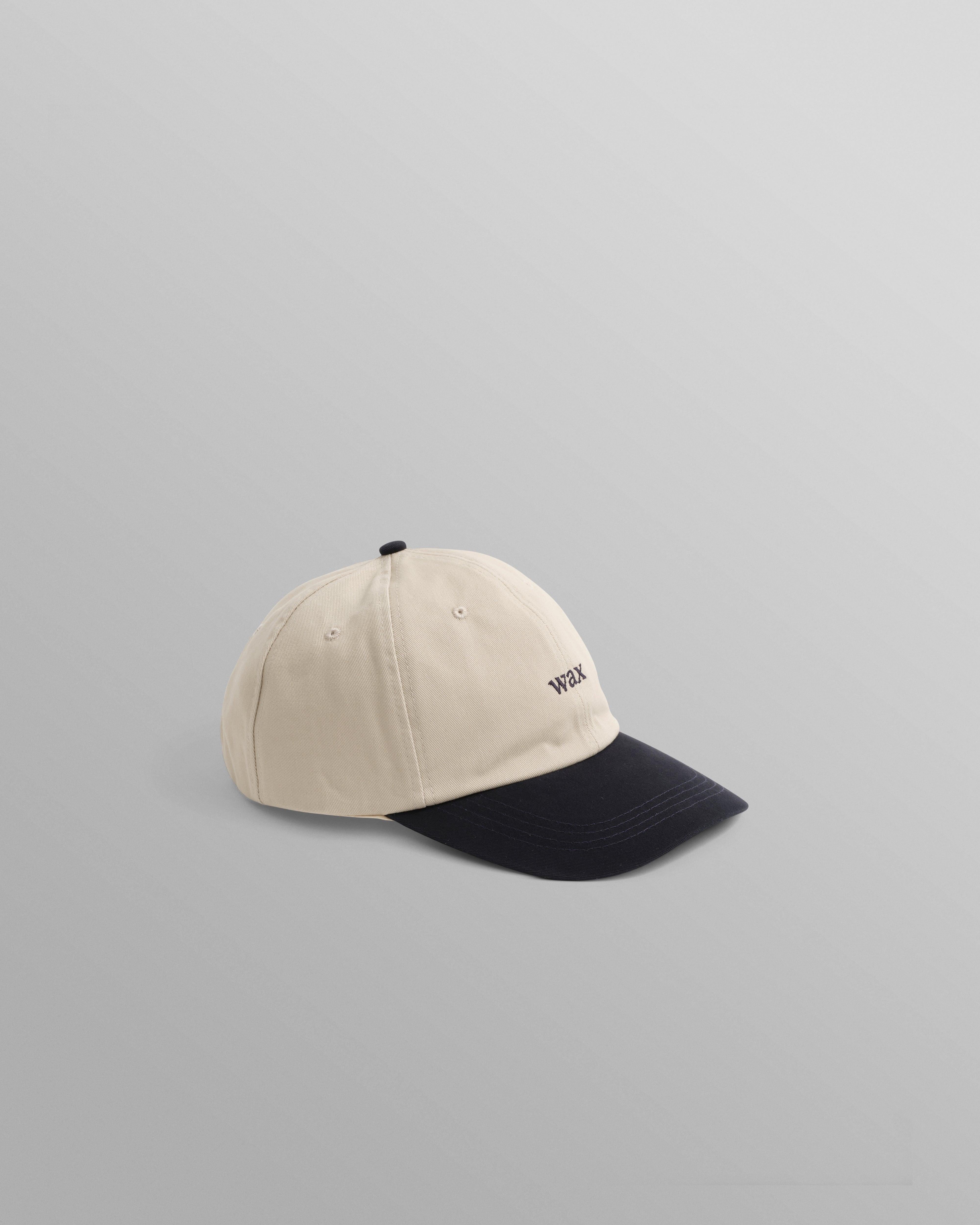 Mørkeblå bomuldsportskasket fra Wax London, Spencer Sport Cap i stenfarvet og navy farve, afslappet og stilfuldt hovedbeklædning